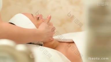 一名女子在美容水疗中心接受治疗师的专业面部按摩